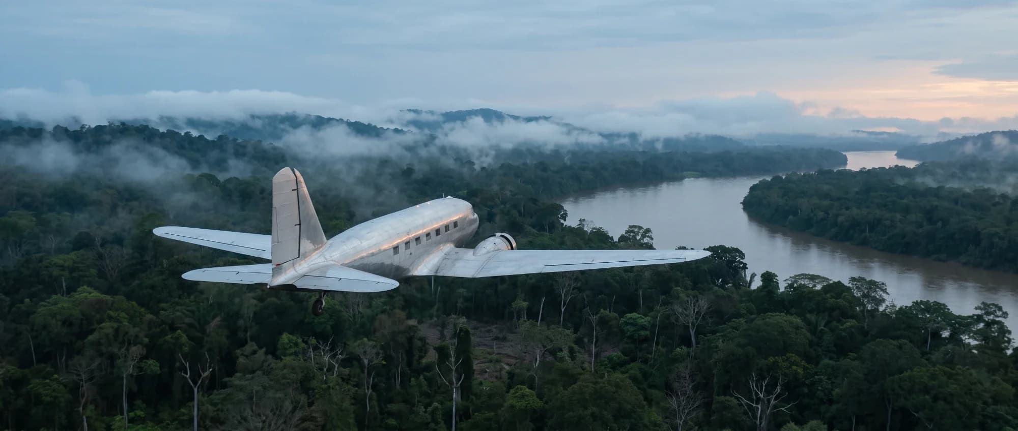 The DC-2 flying away over a jungle river at dusk